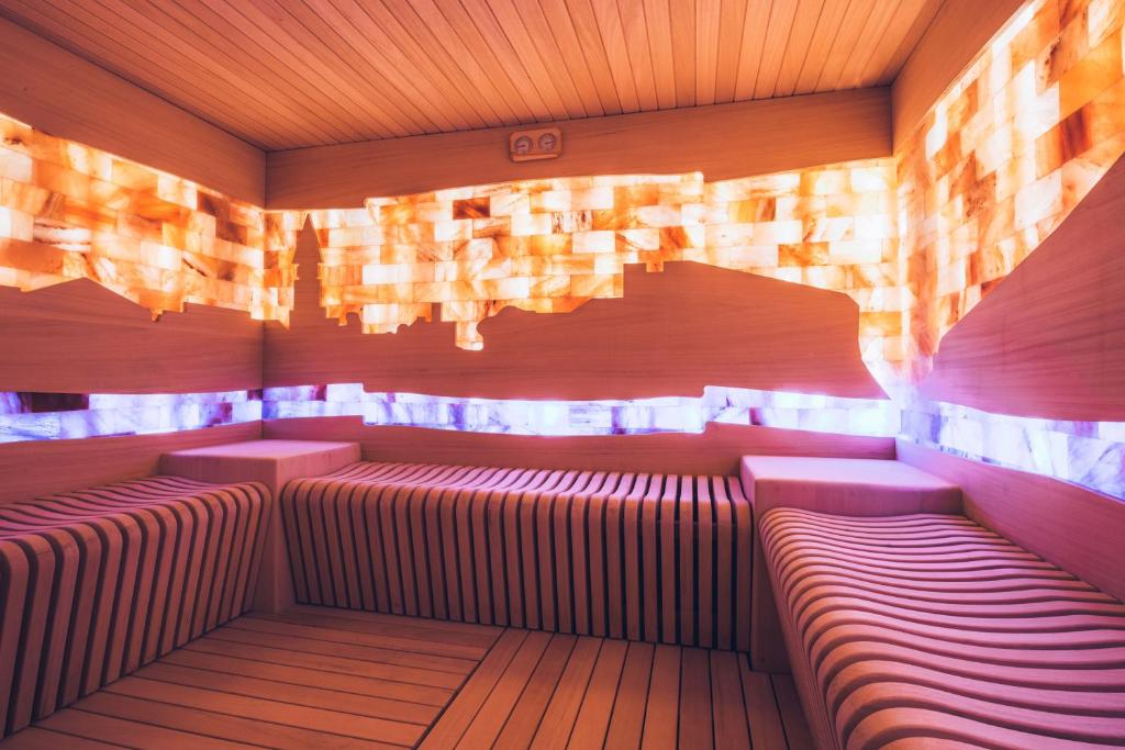 Mūsdienīga sauna ar koka apdari un himēnija akmeņu elementiem, kas rada relaksējošu atmosfēru. Gaismas efekti piešķir telpai unikālu izskatu.