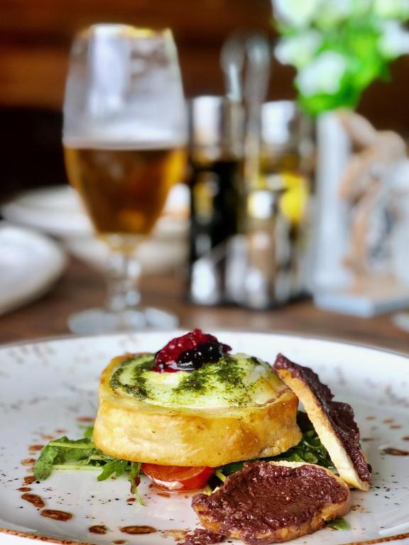 Gourmet ēdiens ar kārtainā mīklā cepumu, zaļumiem un ogu mērci, pasniegts ar salātiem un alus glāzi.