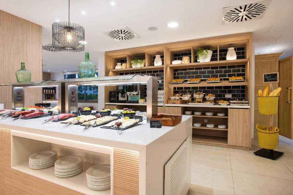 Mūsdienīgs brokastu bufete ar dažādiem ēdieniem, tostarp augļiem, sieriem un maizēm, kā arī elegantu interjeru un apgaismojumu. Ideāla vide, lai izbaudītu brokastis.