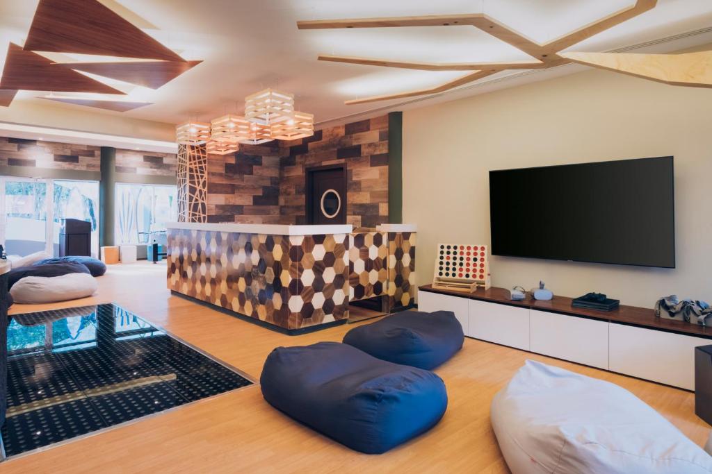 Mūsdienīga koplietošanas telpa ar radošu dizainu, iekārtota ar ērtām sēdvietām un stilīgu reģistratūru. Telpā ir lieli logi un mūsdienīgas apgaismojuma formas.