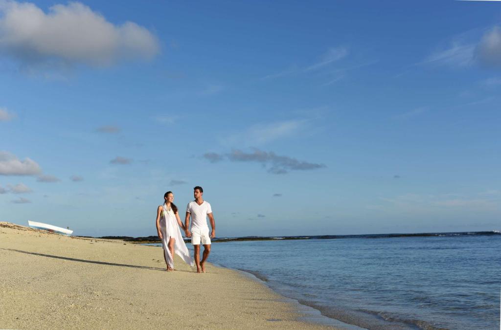 Pāris, kas staigā pa pludmali pie Radisson Blu Poste Lafayette Resort & SPA