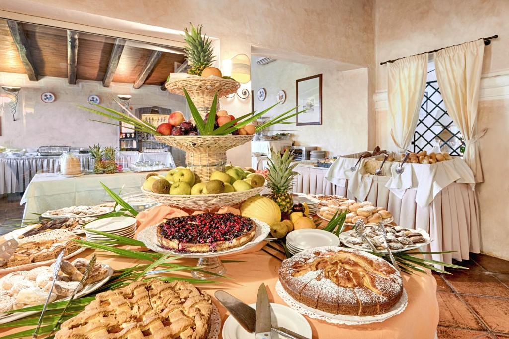 Bagātīgs deserts ar dažādiem kūkām un augļiem, kas izkārtoti uz galda viesību zālē. Šī ainava rada siltu un viesmīlīgu atmosfēru.