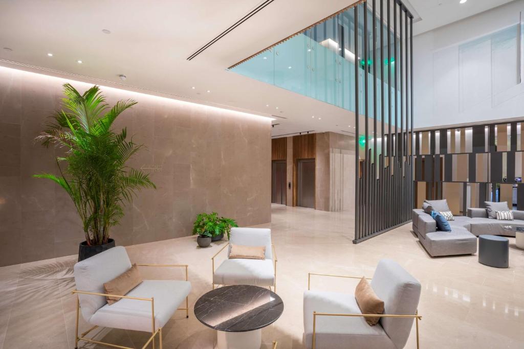 Mūsdienīgs viesnīcas vestibilis ar elegantu dabu, kurā ir zaļie augi, komfortabli dīvāni un stilīgas mēbeles. Gaismas un telpas dizains rada mājīgu atmosfēru.