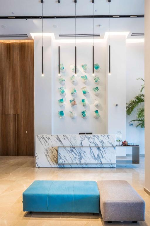 Mūsdienīgs viesnīcas reģistratūras interjers ar stilīgu marmora leti un krāsainu mākslas darbu uz sienas, papildināts ar komfortablām sēdvietām.