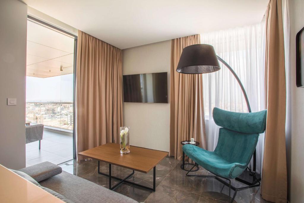 Mūsdienīgs viesnīcas numurs ar plašu skatu, stilīgu turku krēslu un apgaismojuma lampu. Interjerā ir gaiši toņi un eleganta mēbeļu izvēle.