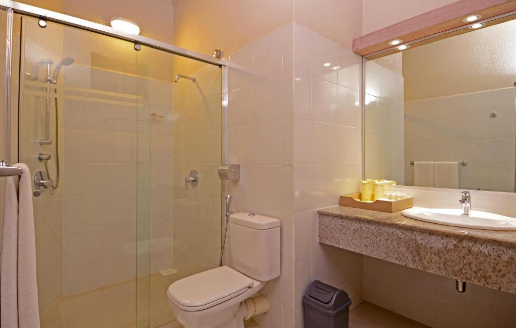 Mūsdienīga vannas istaba ar stikla dušas kabīni, tualeti un akmens izskata izlietni. Telpa ir gaiša un tīra, ar funkcionālu dizainu.