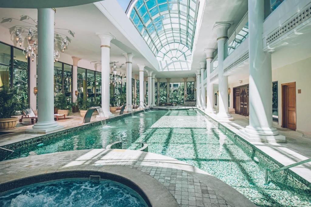 Luksusa spa telpa ar iekštelpu baseinu, ko apgaismo saules gaisma caur stikla jumtu, un elegantām kolonnām. Apkārt baseinam ir zaļi augi un atpūtas zonas.