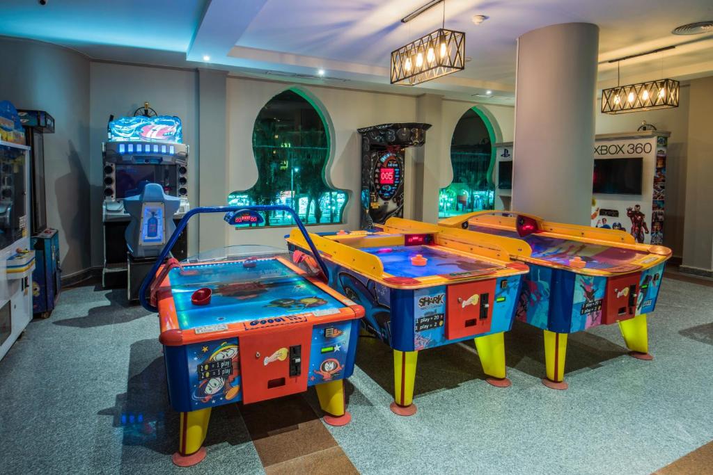 Apskates telpa ar arcade spēlēm, tostarp gaisa hokeja galdiem un citām spēļu mašīnām, kas rada jautru un izklaidējošu atmosfēru.