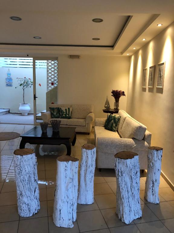 Mūsdienīgs viesistabas interjers ar gaišām tonalitātēm, baltiem koka krēsliem un komfortablu dīvānu. Telpā ir liela durvju atvēršana uz dārzu, kas piešķir svaigumu un gaisīgumu.