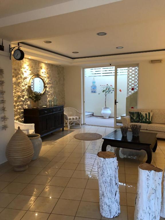 Mūsdienīga un eleganta viesistaba ar dabīgām materiāla akcentiem, kurā redzamas ērti sēdekļi un dekoratīvi elementi. Ievērojama gaismas plūsma no logiem un augu klātbūtne rada relaksējošu atmosfēru.