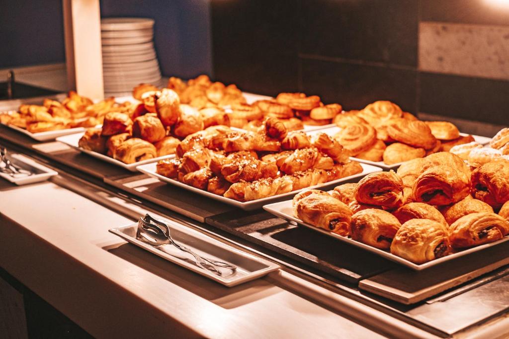 Bakery display featuring an assortment of freshly baked pastries, including croissants and sweet rolls, arranged on elegant platters in a buffet setting.