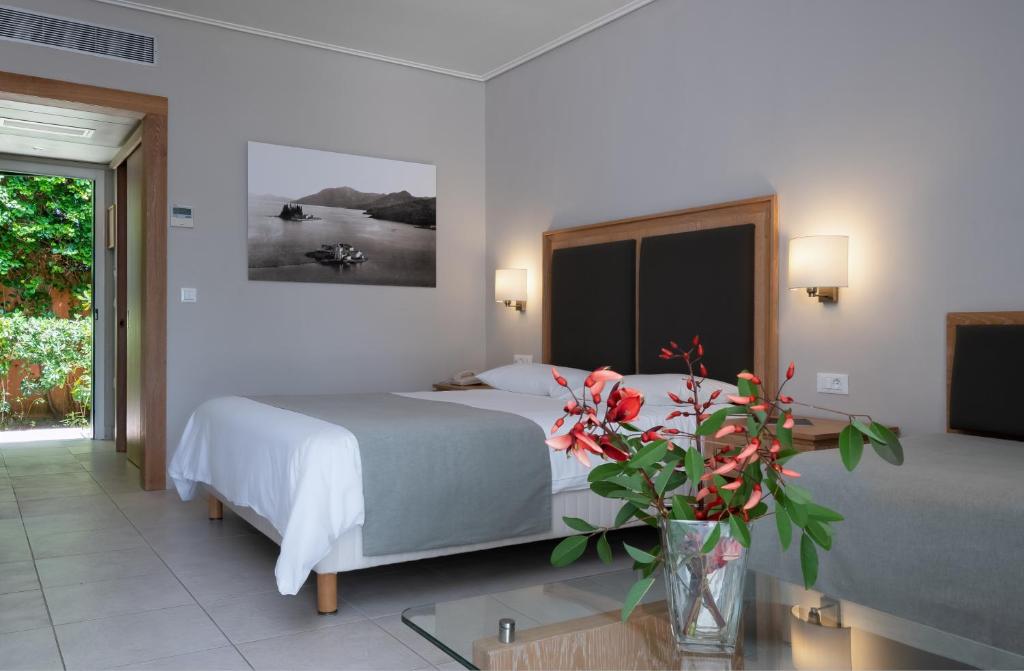 Mūsdienīgs viesnīcas numurs ar divām gultām, elegantu interjeru un skatu uz dārzu. Uz galda ir ziedu kompozīcija, kas piešķir siltumu un mājīgumu telpai.