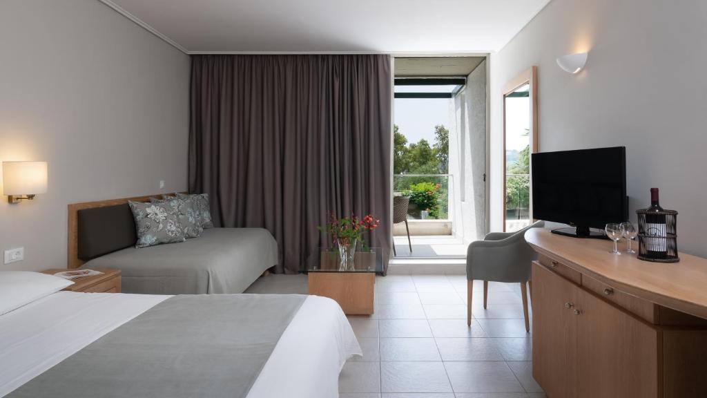 Mūsdienīgs viesnīcas numurs ar divām gultām, televizoru un skatu uz balkonu, kurā redzami koki un ziedi. Interjers ir gaišs un ērts, ar neitrālām krāsām un stilīgu mēbeli.