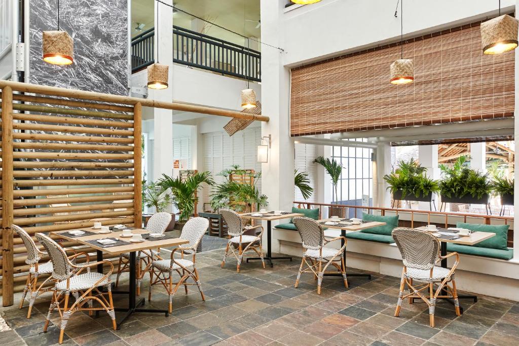 Mūsdienīgs restorāna interjers ar dabīgiem materiāliem, piemēram, koka un rattan krēsliem, zaļām palmas un stilīgu apgaismojumu. Ideāla vieta relaksācijai un ēdiena baudīšanai.