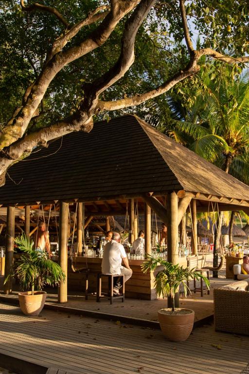 Tropu kafejnīca ar koka konstrukciju, kur apmeklētāji baudījuši laiku zem lieliem kokiem un zālēm, radot relaksējošu atmosfēru.