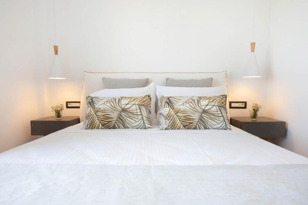 Mūsdienīga guļamistaba ar spilveniem ar augu motīviem un minimālistisku apgaismojumu, radot relaksējošu atmosfēru.