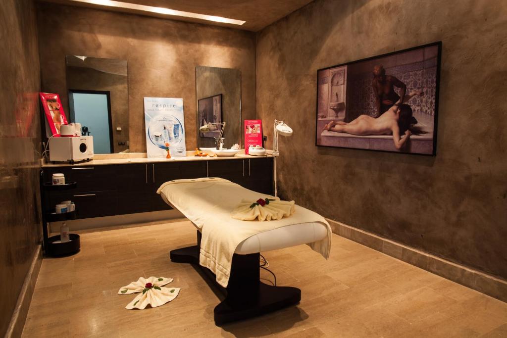 Masažu telpa ar gultu, dekorēta ar ziediem, un attēlu uz sienas. Telpa ir gaiša un relaksējoša, ar modernu aprīkojumu un estētisku interjeru.