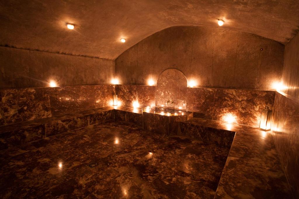 Marmora vannas istaba ar svecēm, radot relaksējošu atmosfēru. Tumša apgaismojuma un elegantas virsmas kombinācija veido mierīgu un greznu vidi.