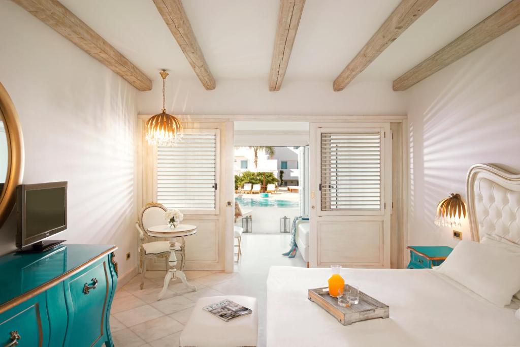 Mūsdienīgs viesnīcas numurs ar gaišu interjeru, kas iekļauj elegantu gultu, izsmalcinātu mēbeļu un skatu uz peldbaseinu. Apgaismojums un dabīgā gaisma rada patīkamu atmosfēru.