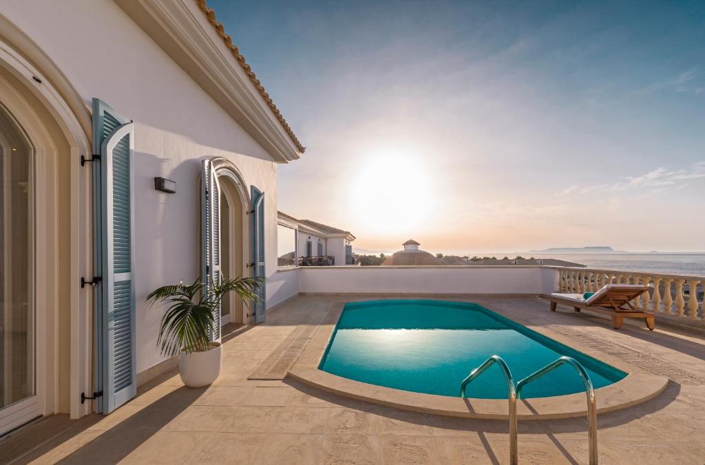 Mūsdienīga villa ar privātu baseinu, kas atrodas pie jūras, ar saule rietam fonā. Šī gleznainā ainava piedāvā relaksējošu atmosfēru un skaistus skatus uz dabu.