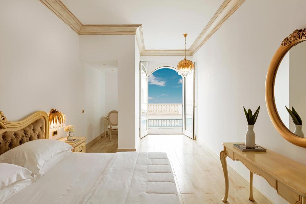 Gaiša un eleganta guļamistaba ar plašu skatu uz jūru, dekorēta ar klasiskām mēbelēm un modernu apgaismojumu. Logi atveras uz saulainu terasi, radot mierīgu atmosfēru.