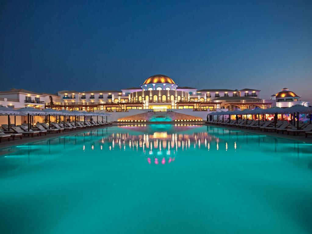 Elegants kūrorts ar skaistu baseinu, kas atspoguļojas vakarā, izgaismots ar mīkstām gaismām. Ideāla vieta relaksācijai un atpūtai.