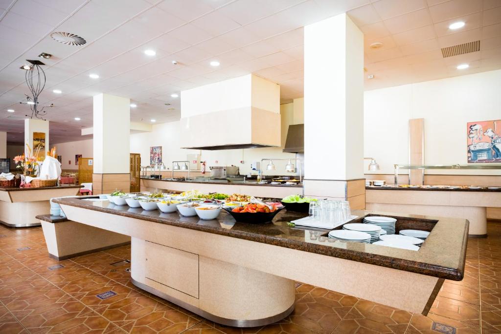 Lielas viesnīcas bufete ar dažādām salātiem un ēdieniem, gaišs interjers un mūsdienīga virtuve. Ideāla vieta brokastīm vai pusdienām.