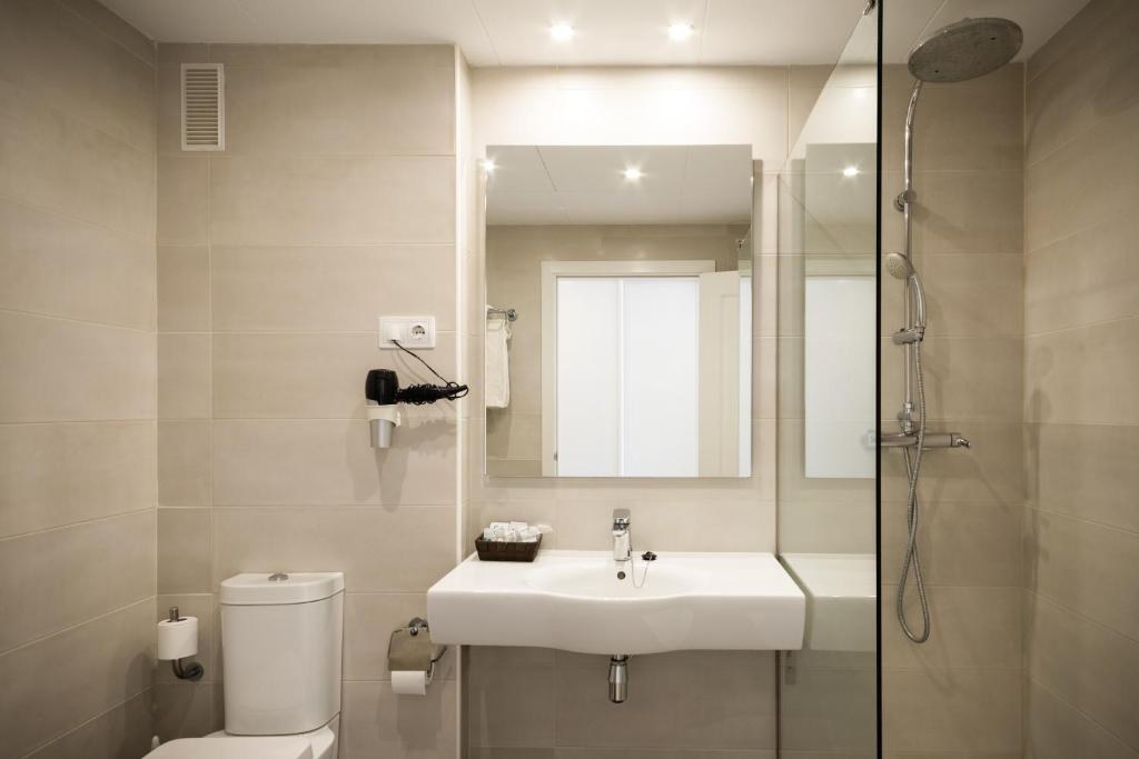 Mūsdienīgs vannas istabas interjers ar dušu, izlietni un tualeti, kas veidots gaišās krāsās. Telpa ir labi apgaismota ar griestu lampām un spoguli.