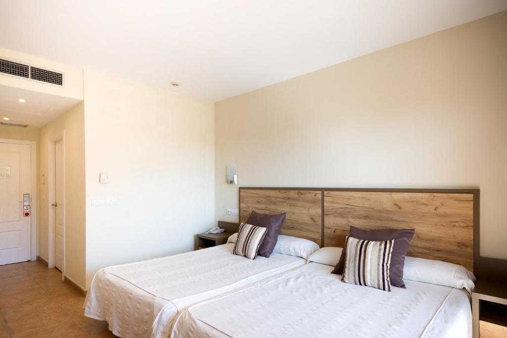 Mūsdienīgs viesnīcas numurs ar divām atsevišķām gultām un koka galvām, dekorēts ar neitrālām krāsām un spilveniem. Interjers veidots, lai nodrošinātu ērtu un relaksējošu atmosfēru.