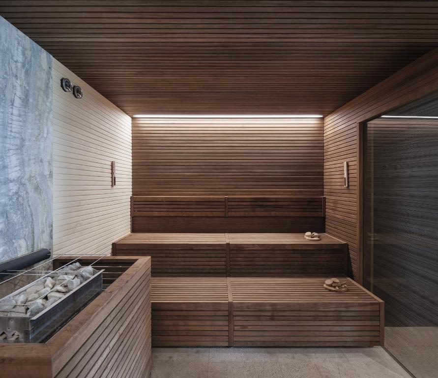 Mūsdienīga sauna ar koka apdari un minimālisma dizainu, apgaismota ar siltu gaismu, radot relaksējošu atmosfēru.