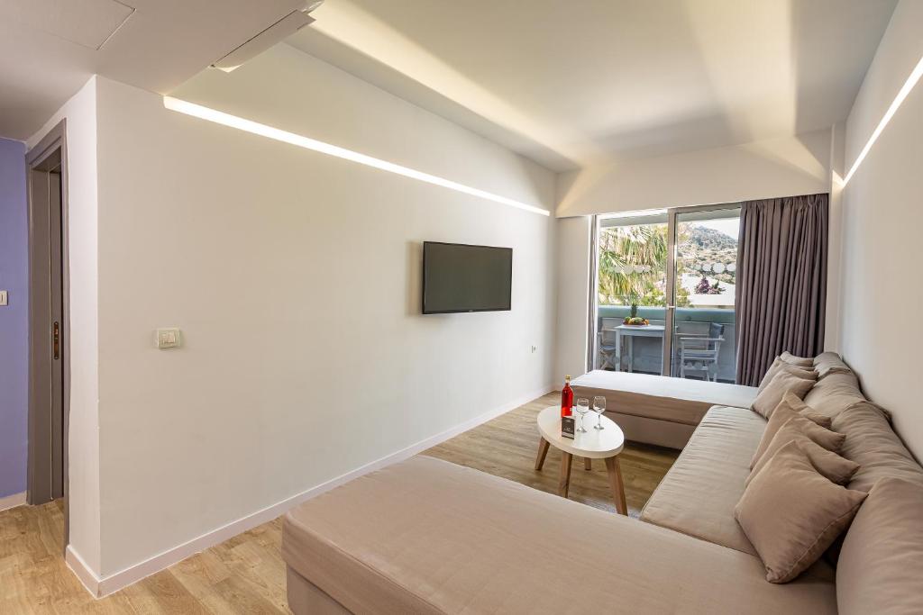 Mūsdienīgs viesnīcas numurs ar ērtu dīvānu, televizoru un balkonu, kas piedāvā skatu uz dabu. Interjers ir gaišs un minimālistisks, radot relaksējošu atmosfēru.