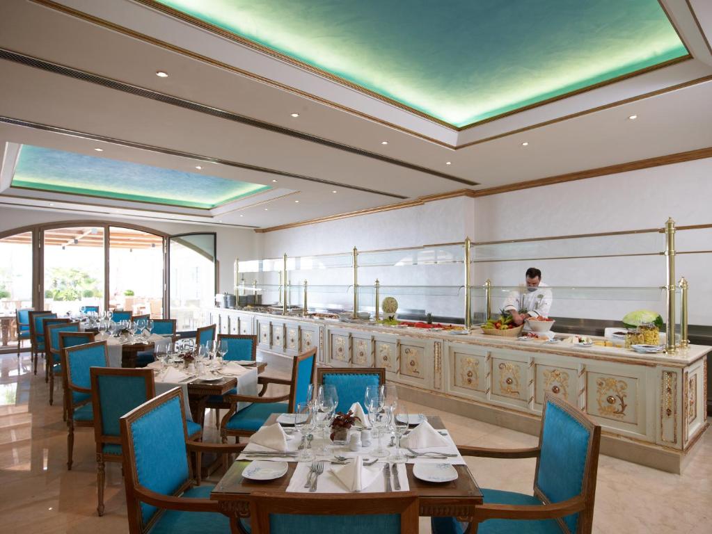 Elegants restorāns ar gaišiem toņiem, zilu krēslu un bufeti, kur pavārs sagatavo ēdienus. Interjerā ir izsmalcināta apdare un liela logs, kas piedāvā skatu uz ārtelpu.