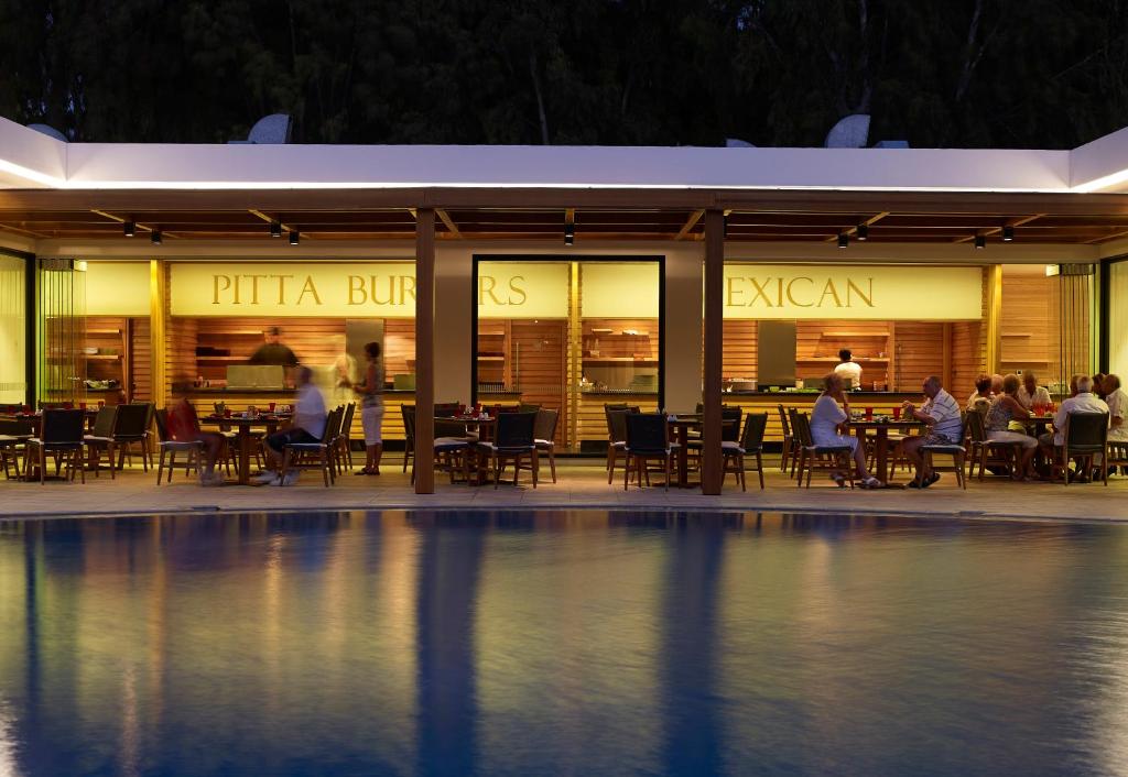 Restorāns ar atvērtu terasi, kas piedāvā pitas burgerus un meksikāņu ēdienus, atrodas pie baseina. Gaismas atmosfēra rada patīkamu vakara noskaņu.