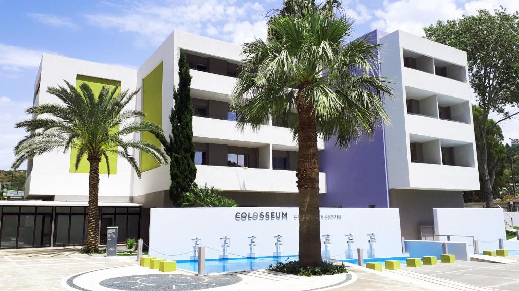 Mūsdienīga ēka ar palmu kokiem un krāsainu fasādi, kas kalpo par Colosseum sporta centru. Apkārt ir plaša teritorija ar ūdens elementiem un mūsdienīgu dizainu.