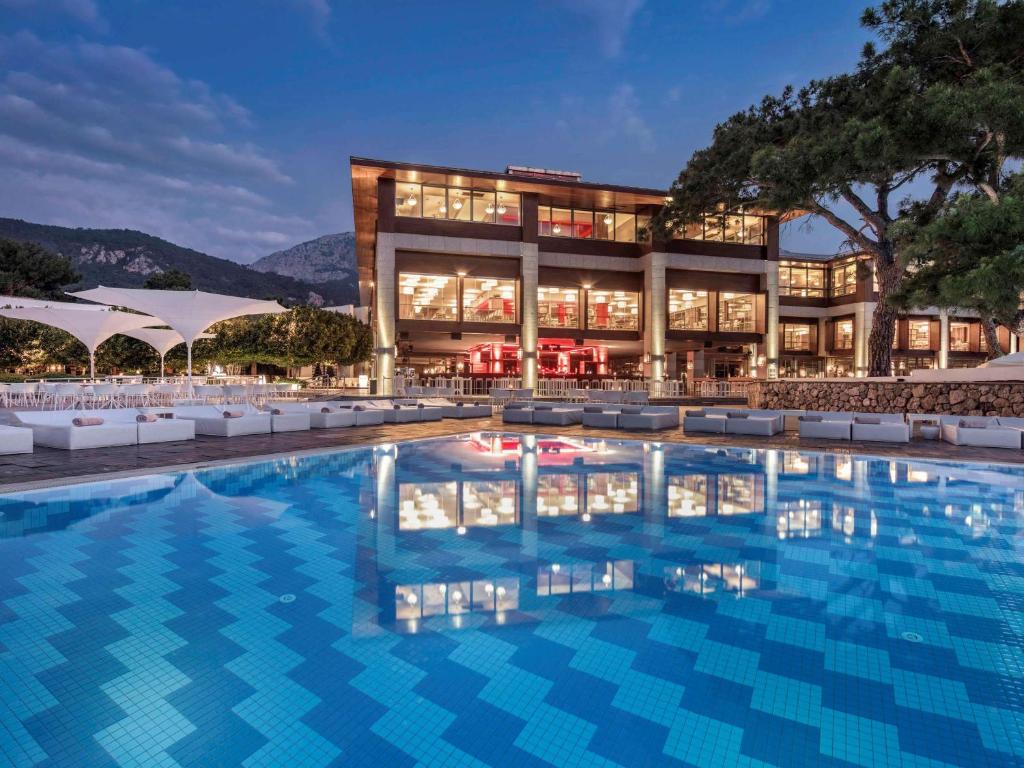 Rixos Sungate - Baseins un viesnīca piekrastē ar kalnu fona