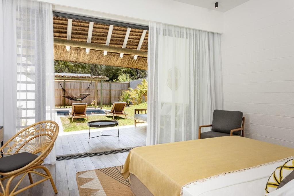 Mūsdienīgs, gaišs numurs ar skatu uz dārzu, kurā ir šūpuļtīkls un sauļošanās krēsli. Telpā ir ērta gulta un rattan krēsls, radot relaksējošu atmosfēru.