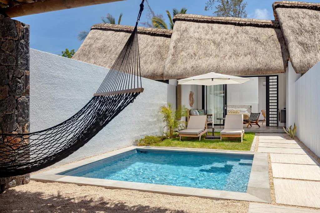 Mūsdienīga atpūtas zona ar peldbaseinu, šūpuļtīklu un sauļošanās krēsliem, ko ieskauj zaļumi un mājīgas struktūras. Ideāla vieta relaksācijai un mierīgai atpūtai.