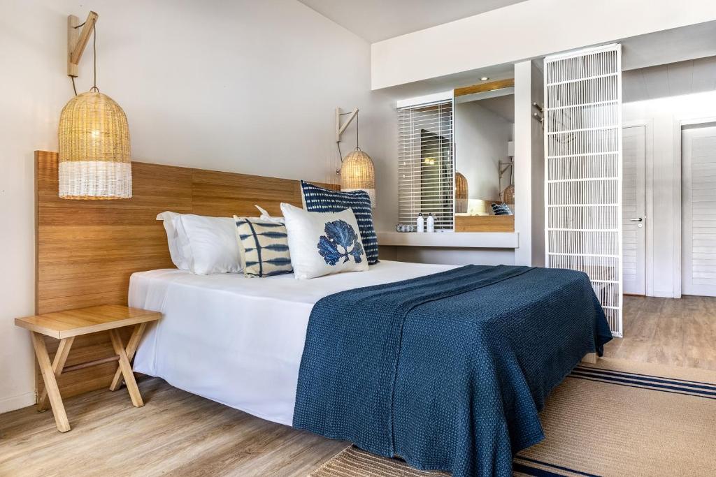 Mūsdienīgs guļamistabas interjers ar koka gultu, dekoratīvām spilveniem un siltām gaismas spuldzēm. Telpa ir ērti iekārtota ar dabīgiem materiāliem un mierīgu krāsu paleti.