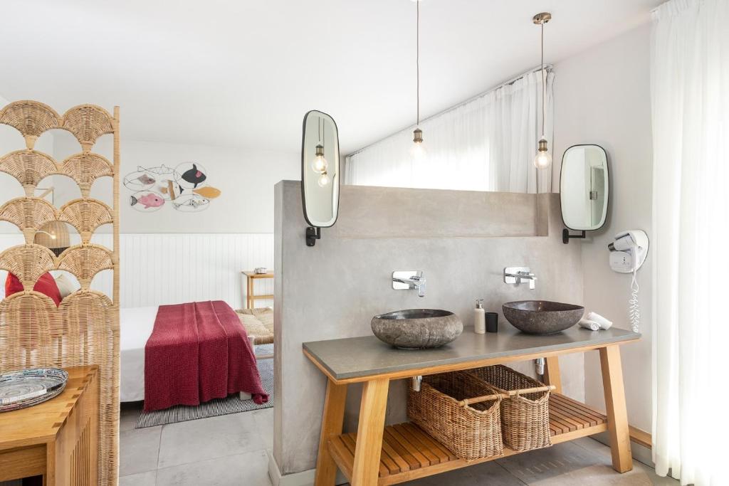 Mūsdienīgs vannas istabas interjers ar divām akmens izlietnēm, koka plauktu un rotājošu ekrānu, kas nodrošina privātumu. Svaigā, gaišā telpā ir redzamas modernās apgaismojuma ierīces un stilīgi aksesuāri.