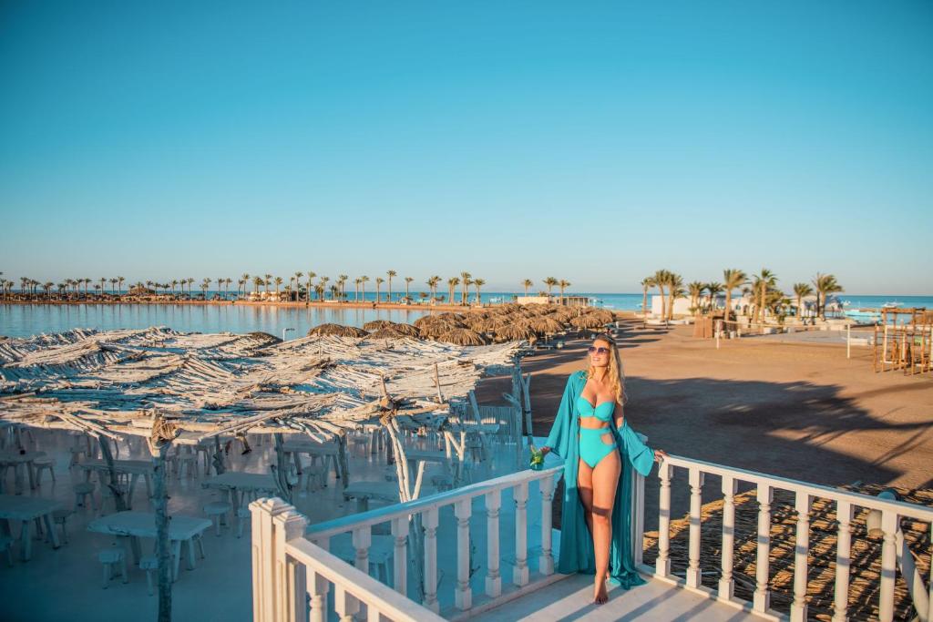 Sieviete pludmalē pie Meraki Resort, tērpta ziliem peldkostīmos.