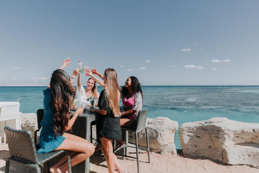 Draugu grupa svin pie Meraki Resort, baudot kokteiļus piekrastē.