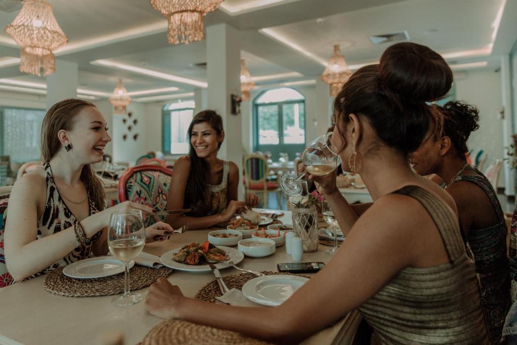 Sievietes izbauda maltīti Meraki Resort restorānā ar elegantiem apgaismojumiem.