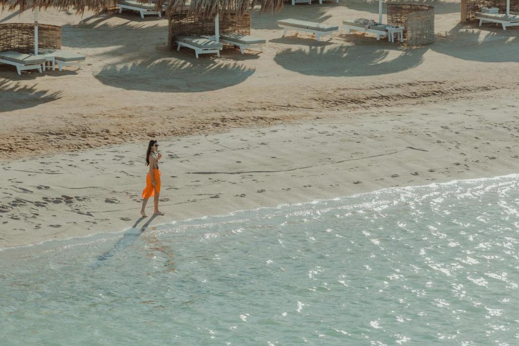 Sieviete staigā pa pludmali Meraki Resort piekrastē.