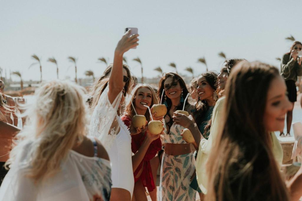 Jaunieši svin un fotografējas pludmalē pie Meraki Resort.