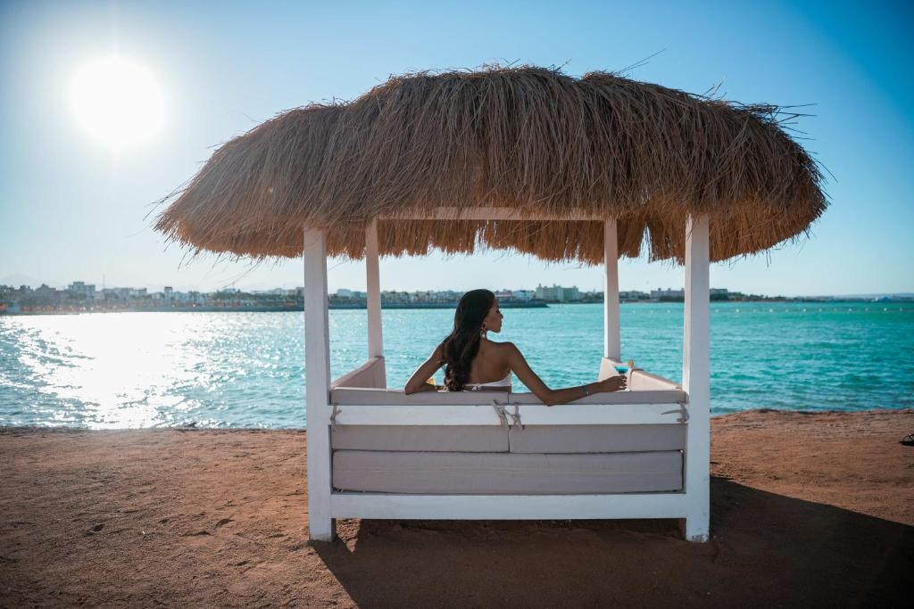 Sieviete relaksējas zem salmu nojumes pie Meraki Resort, piekrastē