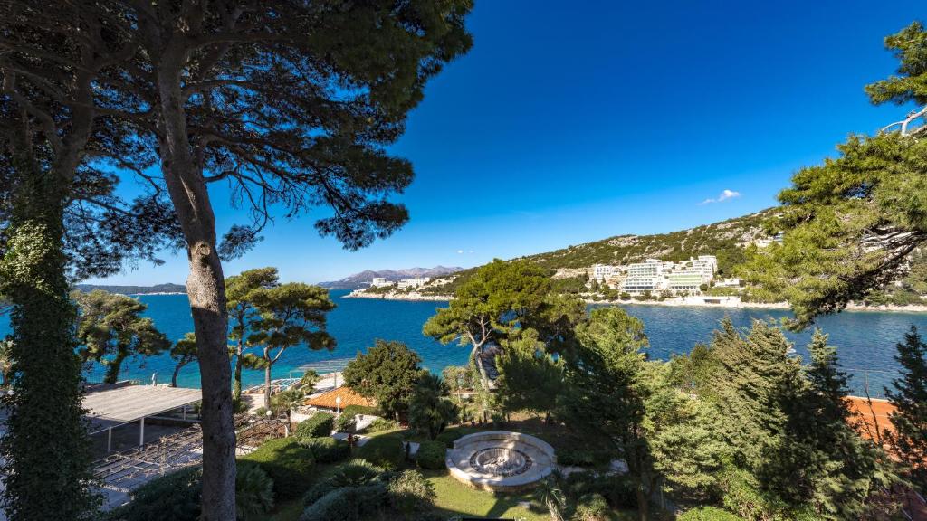 Skaists skats uz jūru, apzaļumotu krastu un kalniem, kas atspoguļo mierīgu un gleznainu ainavu. Dabas elementi un zils debesis rada relaksējošu atmosfēru.