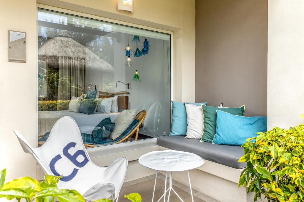 Mūsdienīgs atpūtas stūris ar komfortablu dīvānu un spilveniem, skats uz guļamistabu. Svaiga zaļumi un stilīgs galdiņš papildina relaksējošo atmosfēru.