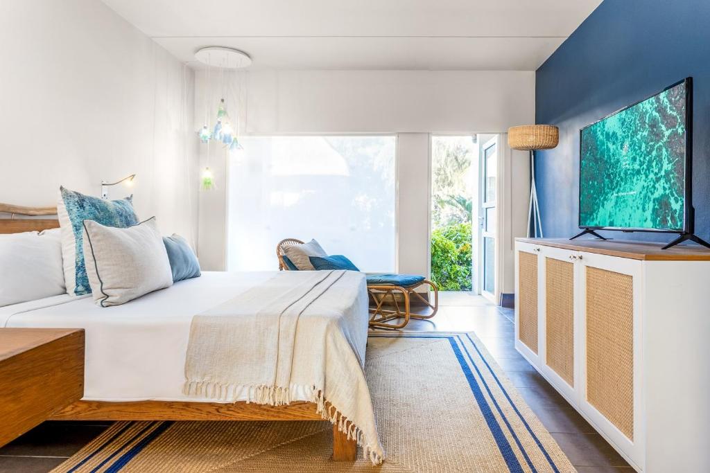 Mūsdienīga viesnīcas numura interjers ar plašu gultu, dīvānu un televizoru, radot relaksējošu atmosfēru. Logi nodrošina dabīgu apgaismojumu un skatu uz dārzu.