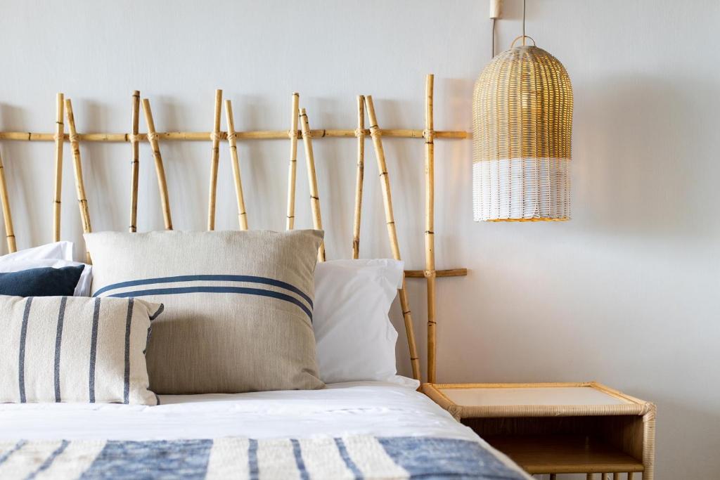 Mūsdienīgs guļamistabas interjers ar bambusa gultas galvgali, dekoratīviem spilveniem un stilīgu lampu. Rāmie toņi un dabīgas materiāla akcenti rada relaksējošu atmosfēru.