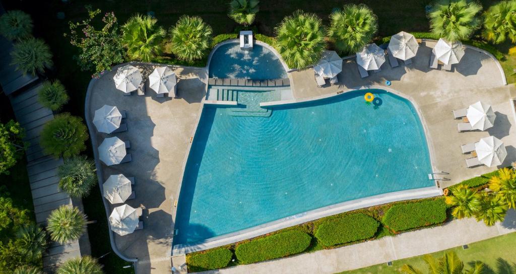 Katathani Phuket Beach Resort baseins ar saulessargiem un zaļām palmu ainavām.